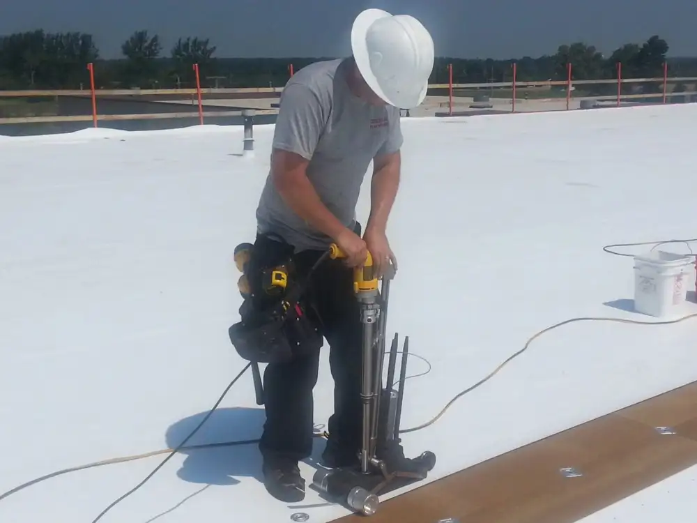 A man in white hat and black pants standing on top of a building.