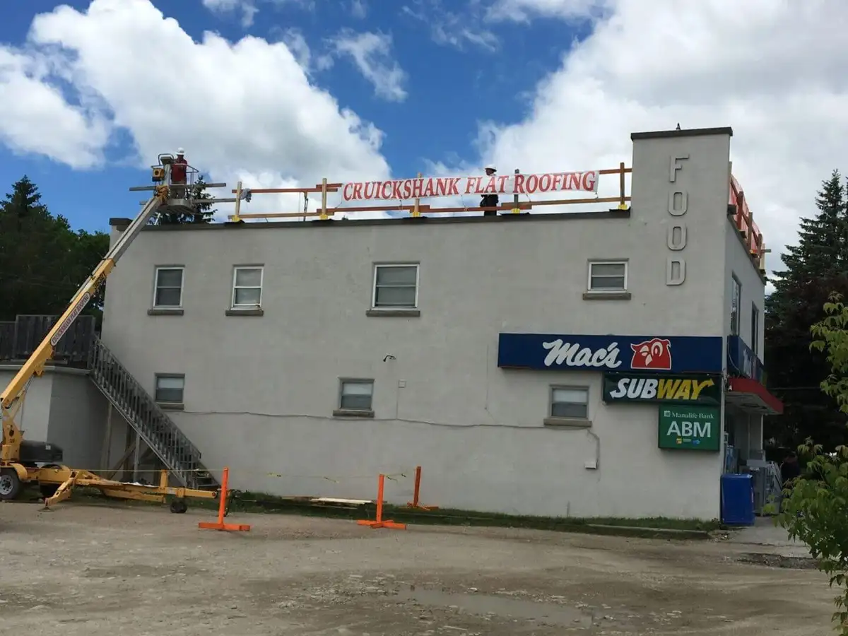 A flat-roof building with the Cruickshank rooftop crew and a lift