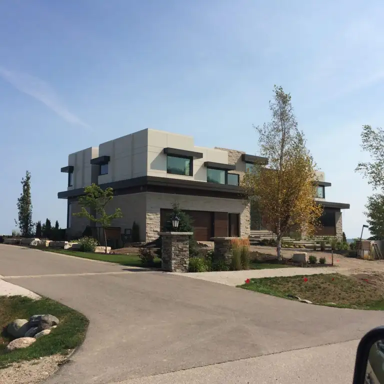 A light stone contemporary house with large windows and a flat roof