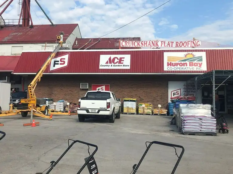 A white Cruickshank Flat Roofing truck parked in front of a building